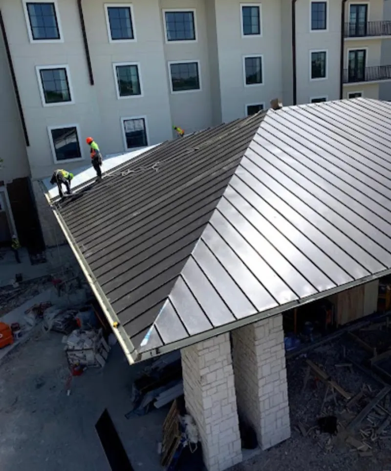 Crew installing standing seam metal roof panels on a commercial project in Rockcreek